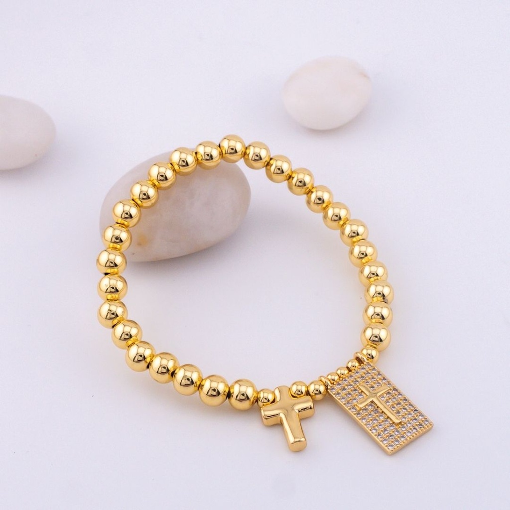 Elegante pulsera elastica con colgante de cruz y bolitas en baño 18k