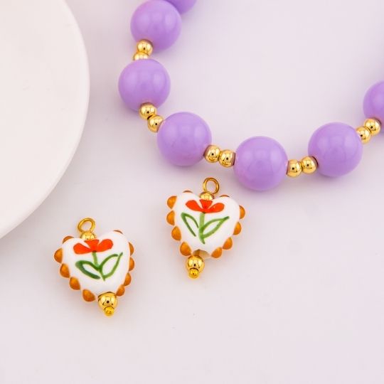 Dije de ceramica vitrificado en forma de corazon con diseño de flor baño 18k